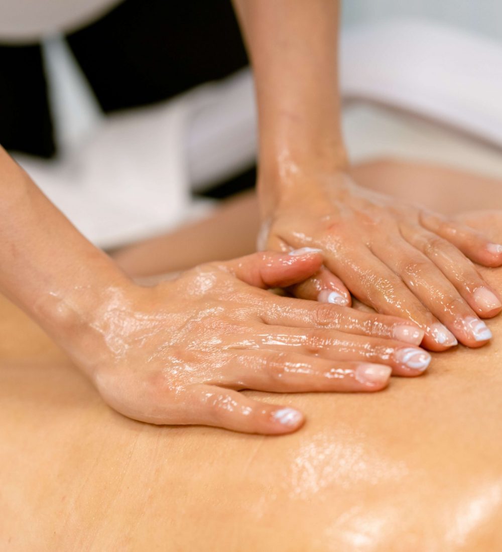 Woman receiving a back massage with massage candle oil. Body care treatment in a beauty centre.