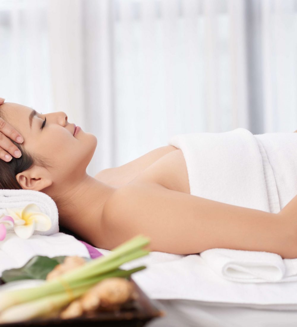 Smiling pretty young woman getting relaxing head massage